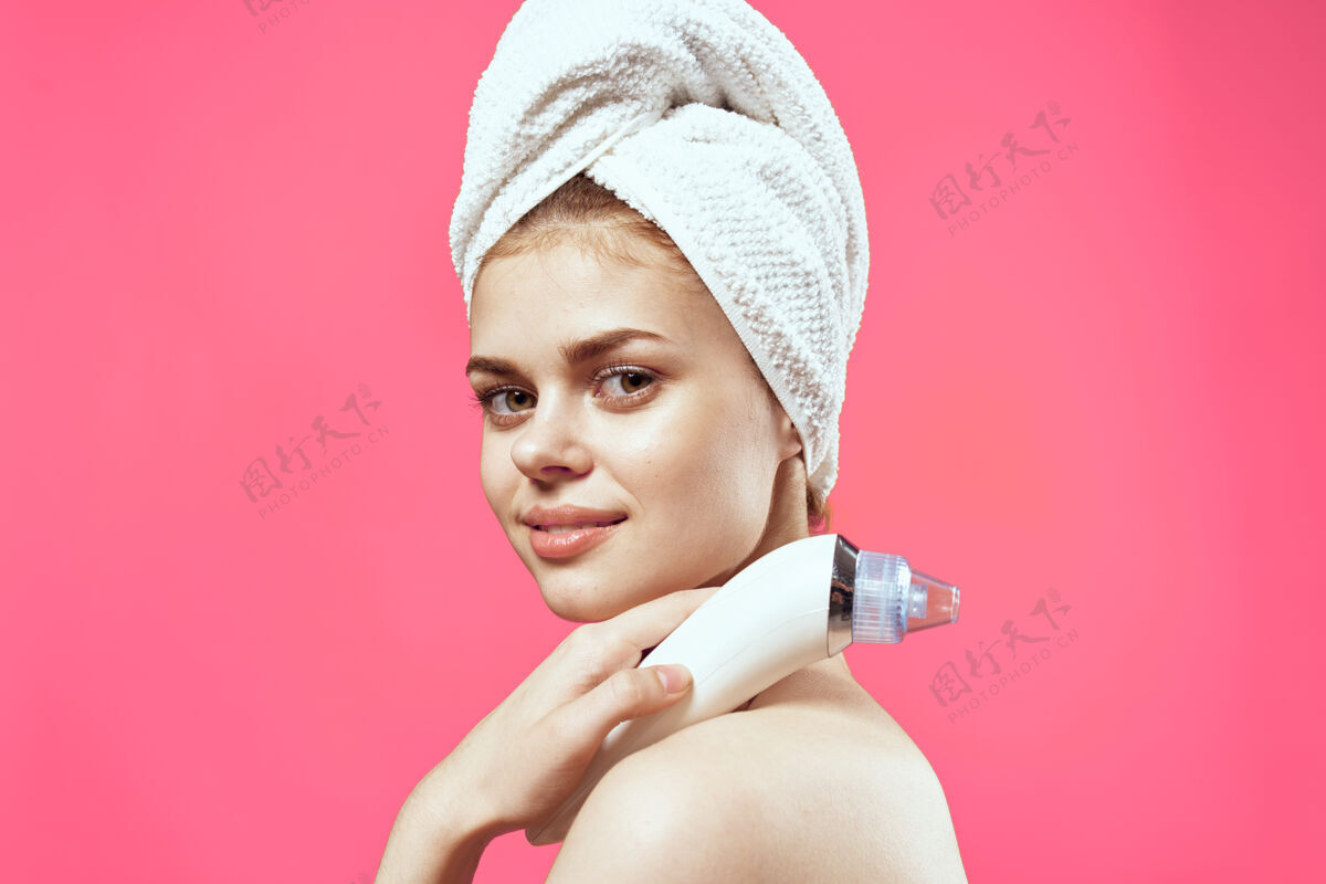 放松女人头上拿着毛巾 手上拿着按摩器 皮肤护理剪成了粉红色的墙皮肤超声波清洁