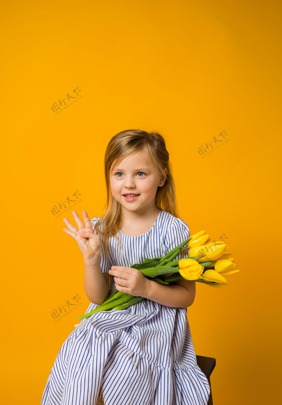 金发快乐的小女孩 带着一束黄色的郁金香 在黄色的花上伸出四个手指持有四给予