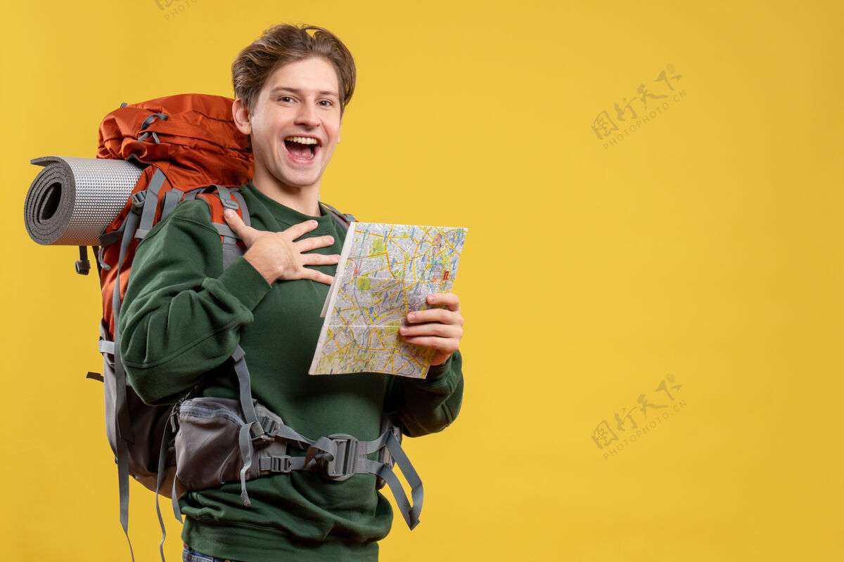 黄色正面图年轻男子背着背包拿着地图旅游地图旅游