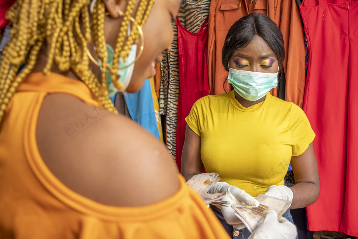 购物特写镜头：一位非洲女性戴着乳胶手套和口罩 在一家商店用现金付款销售联系人女人