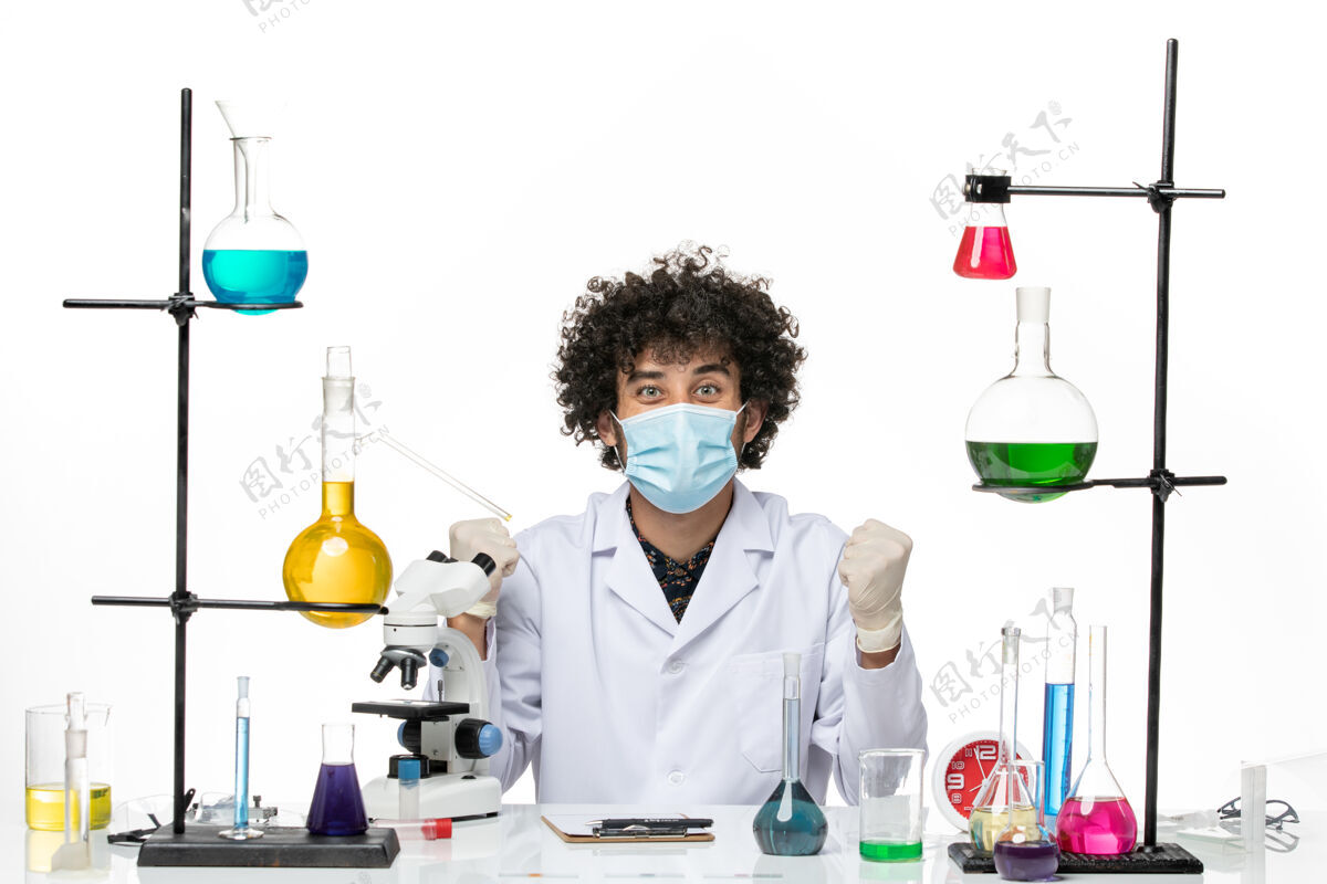 医生正面图：穿着白色医疗服 戴着口罩的男性化学家正坐在白色的空间里欢欣鼓舞化学实验室外套前面