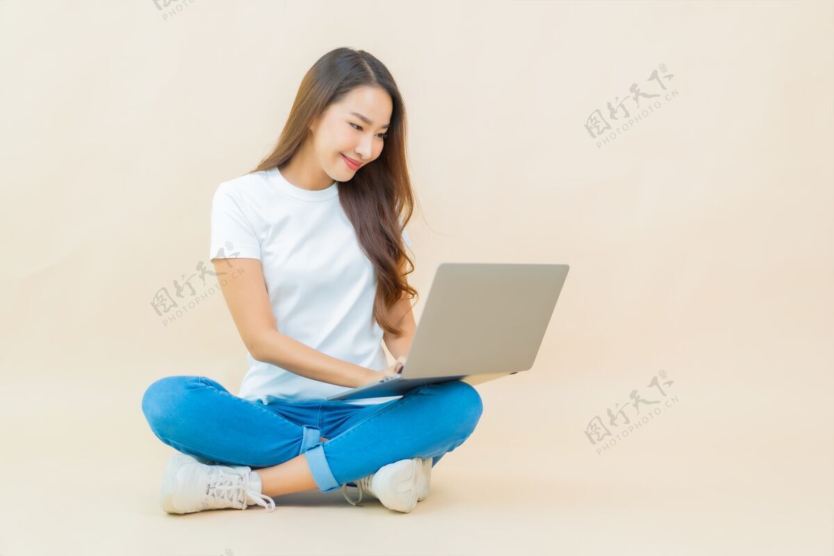 聪明肖像美丽的亚洲年轻女子用笔记本电脑在米色使用科技工作