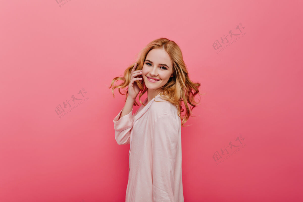 明亮穿着棉质睡衣的自信女孩在玩她的头发欢快的女模特穿着浅粉色睡衣的室内照片迷人微笑年轻