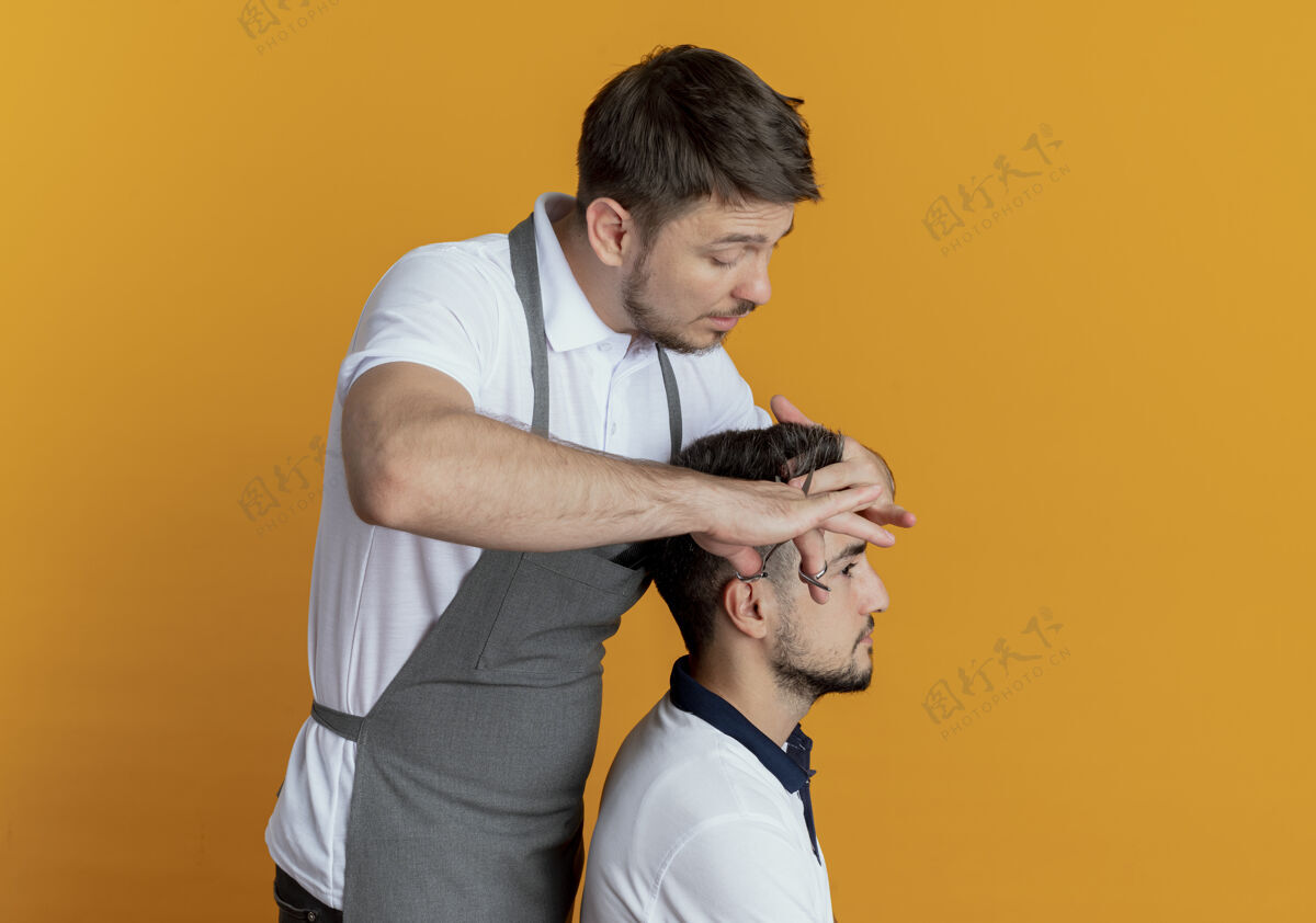 理发师穿着围裙的理发师在橙色背景上用满意客户的剪刀剪头发围裙剪头发