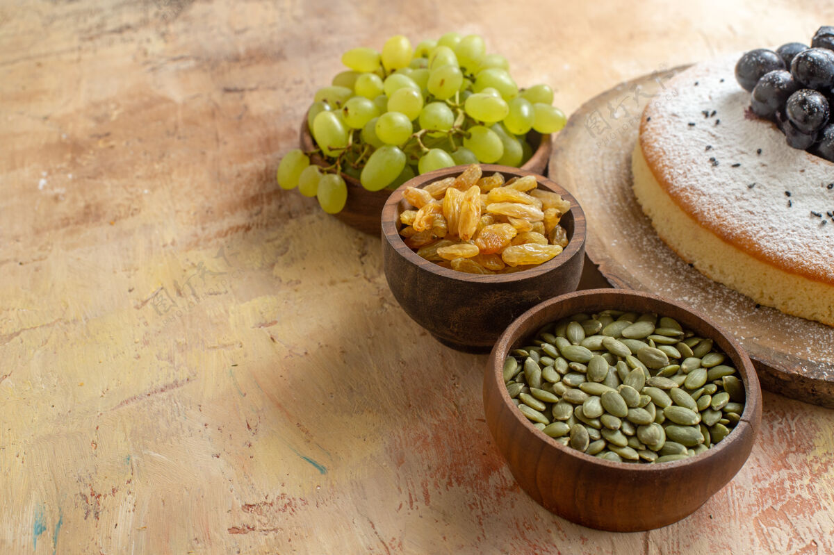 健康侧面特写图一个蛋糕一碗绿葡萄葡萄干南瓜籽一个蛋糕在黑板上南瓜食用坚果饮食