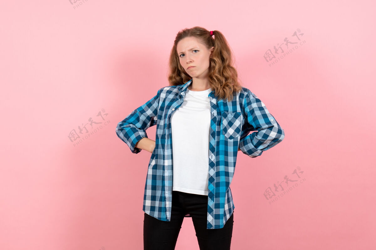 漂亮正面图身着蓝色格子衬衫的年轻女性在粉色背景上摆姿势青春情感女孩儿童模特时尚人肖像情绪