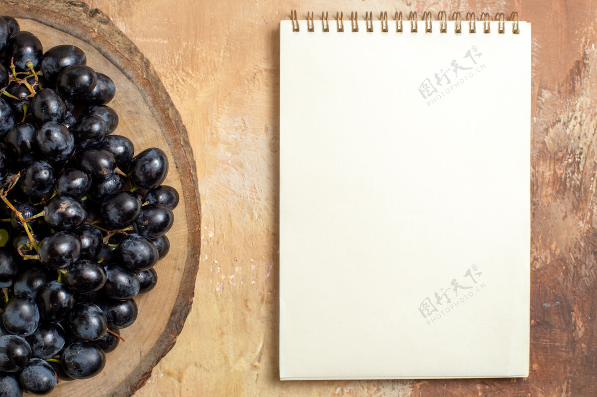 笔记本顶部特写查看葡萄串黑葡萄在木制砧板白色笔记本葡萄健康配料