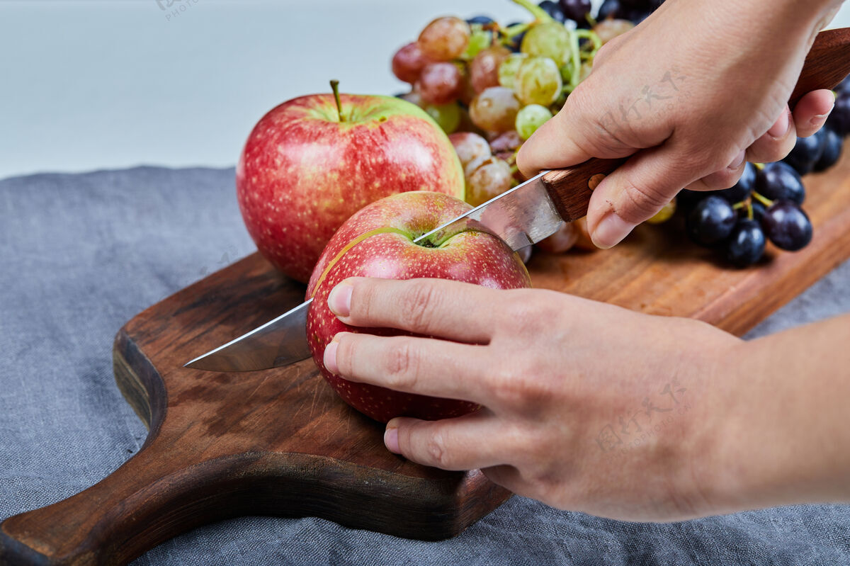 新鲜厨师用刀子在板上切一个红苹果产品极简品质