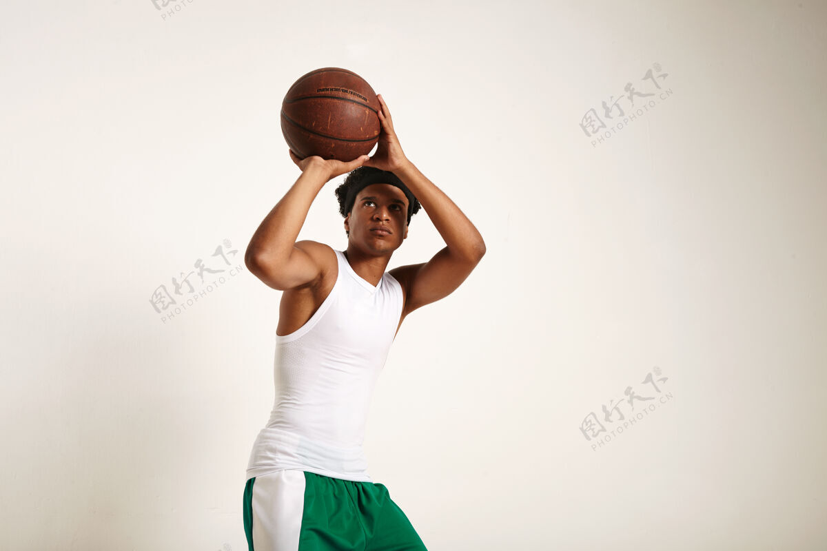 观点聚焦适合年轻的非洲裔美国球员在白色和绿色的篮球装备扔一个老式篮球隔离在白色投掷团队投掷