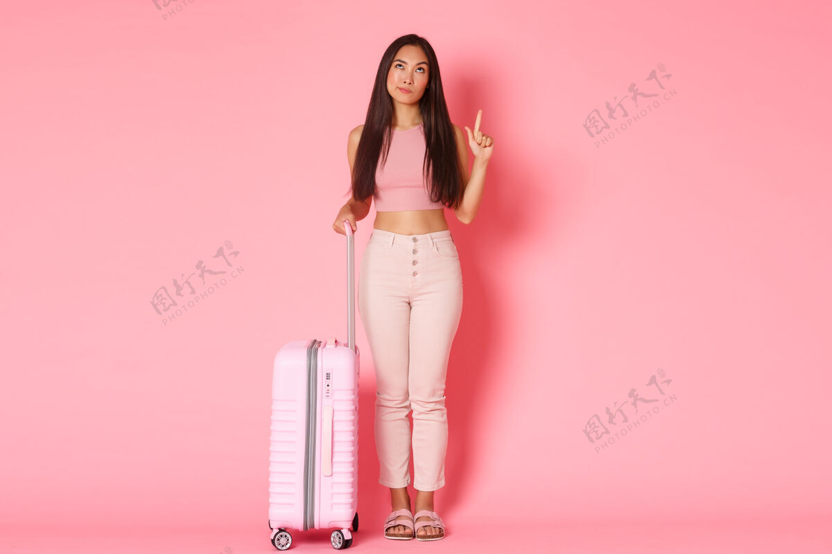 指点向上带着手提箱的年轻女子旅行社旅游时尚