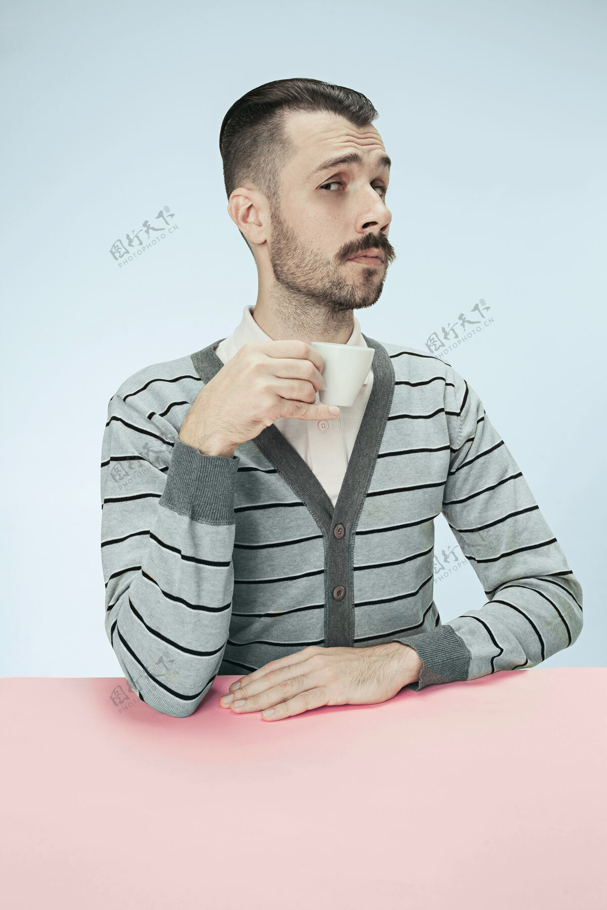 早餐孤独的男人坐在粉红色的工作室里 手里拿着一杯咖啡 看上去很悲伤悲伤表情杯子