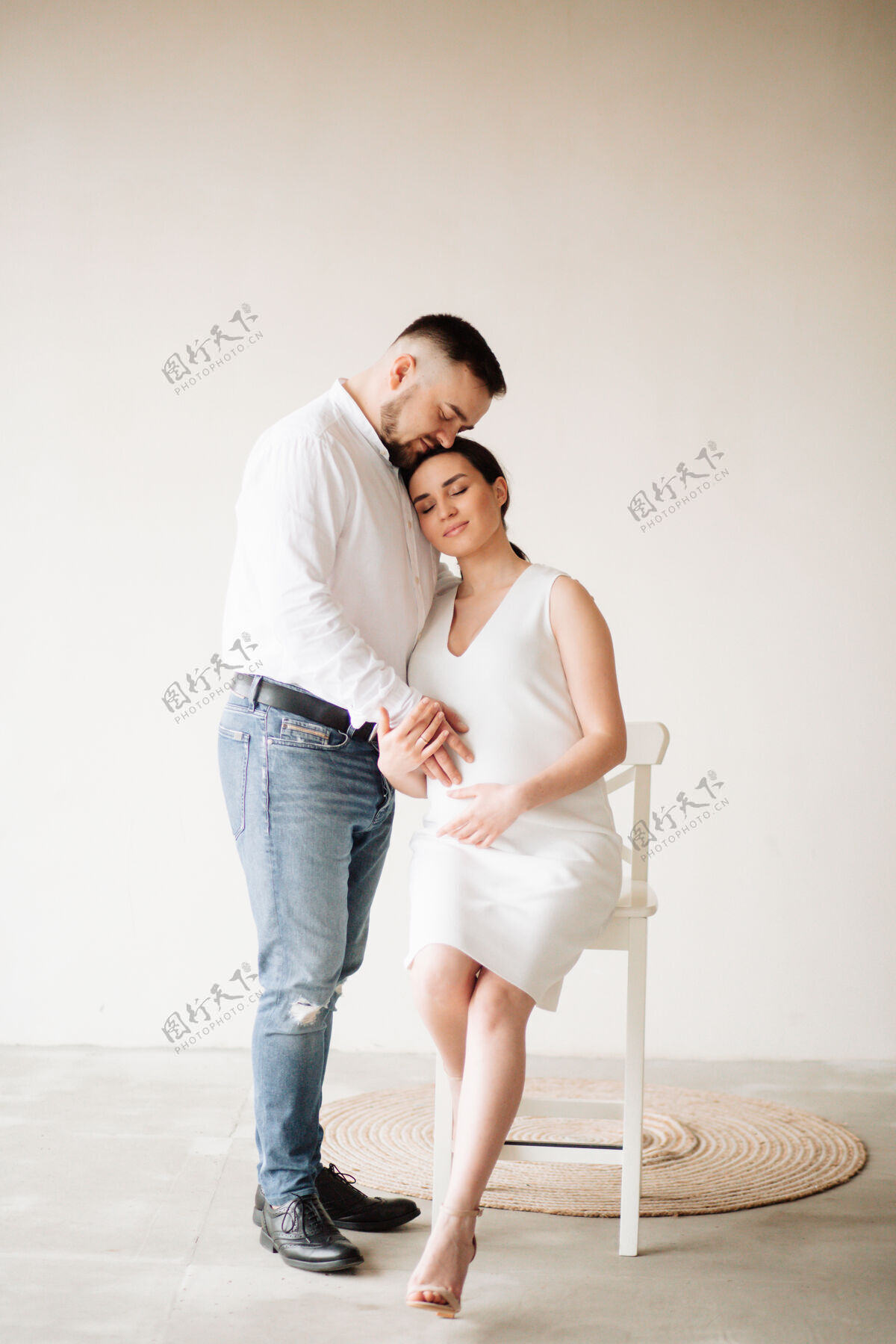 姿势快乐迷人的孕妇和她的丈夫在摄影棚里合影期望出生腹部