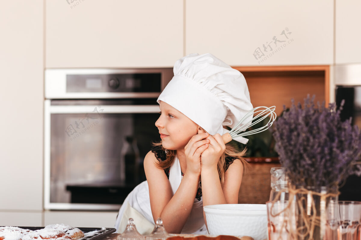 肖像厨房里一个戴着白色厨师帽的漂亮小女孩烘焙童年围裙
