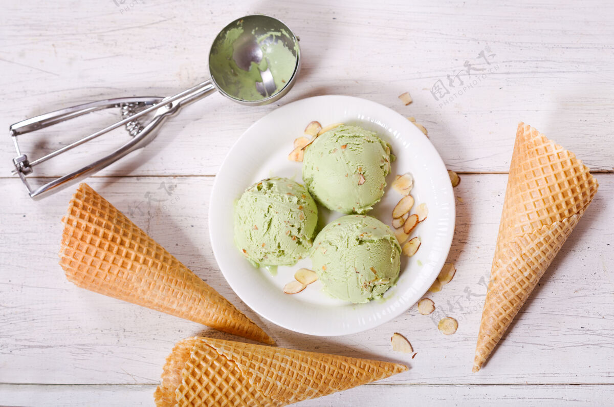 奶油木桌上放着一盘开心果冰淇淋勺和华夫饼筒 俯视图水果新鲜奶制品