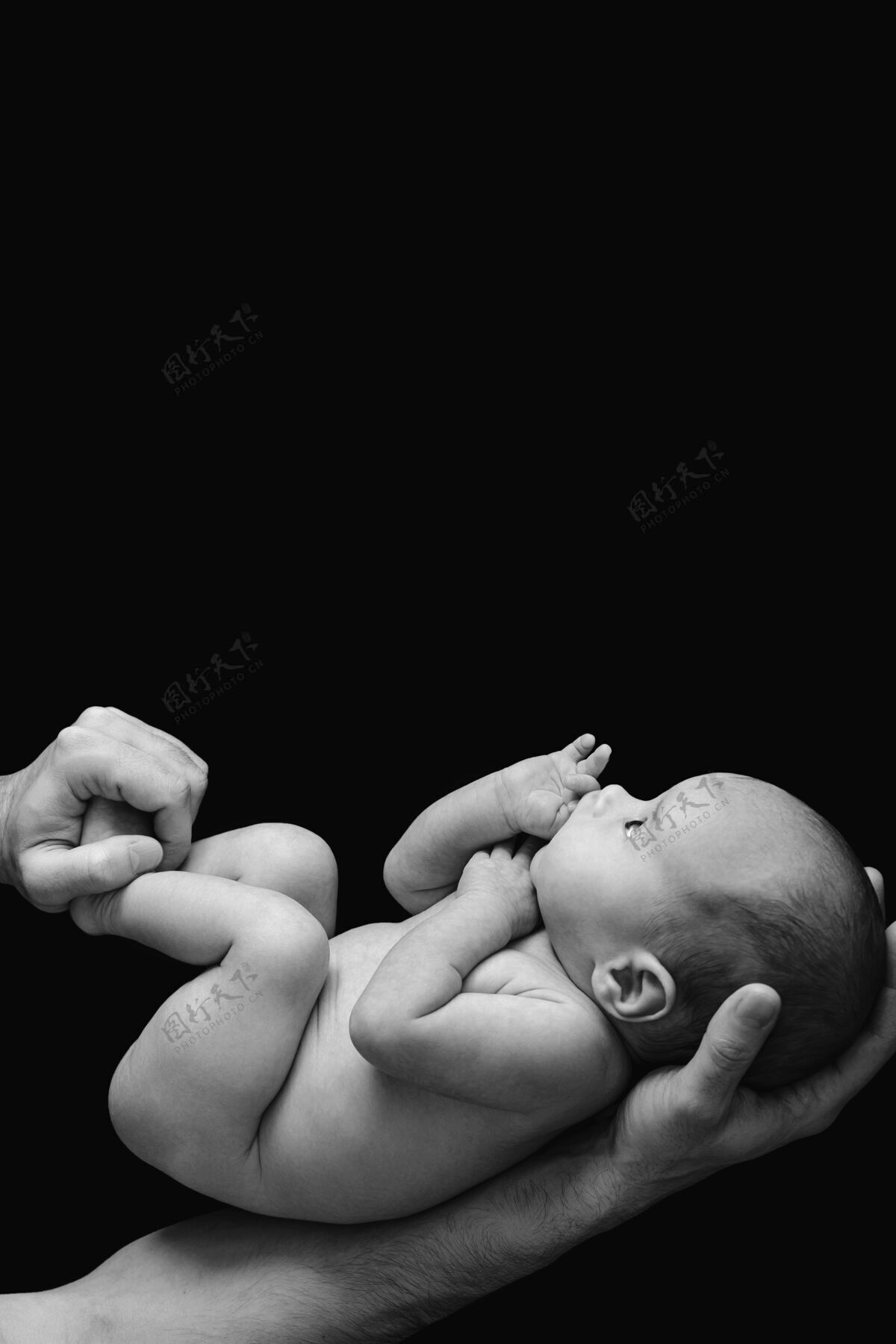 男孩可爱的新生婴儿在爸爸的手上黑墙为人父母有趣概念