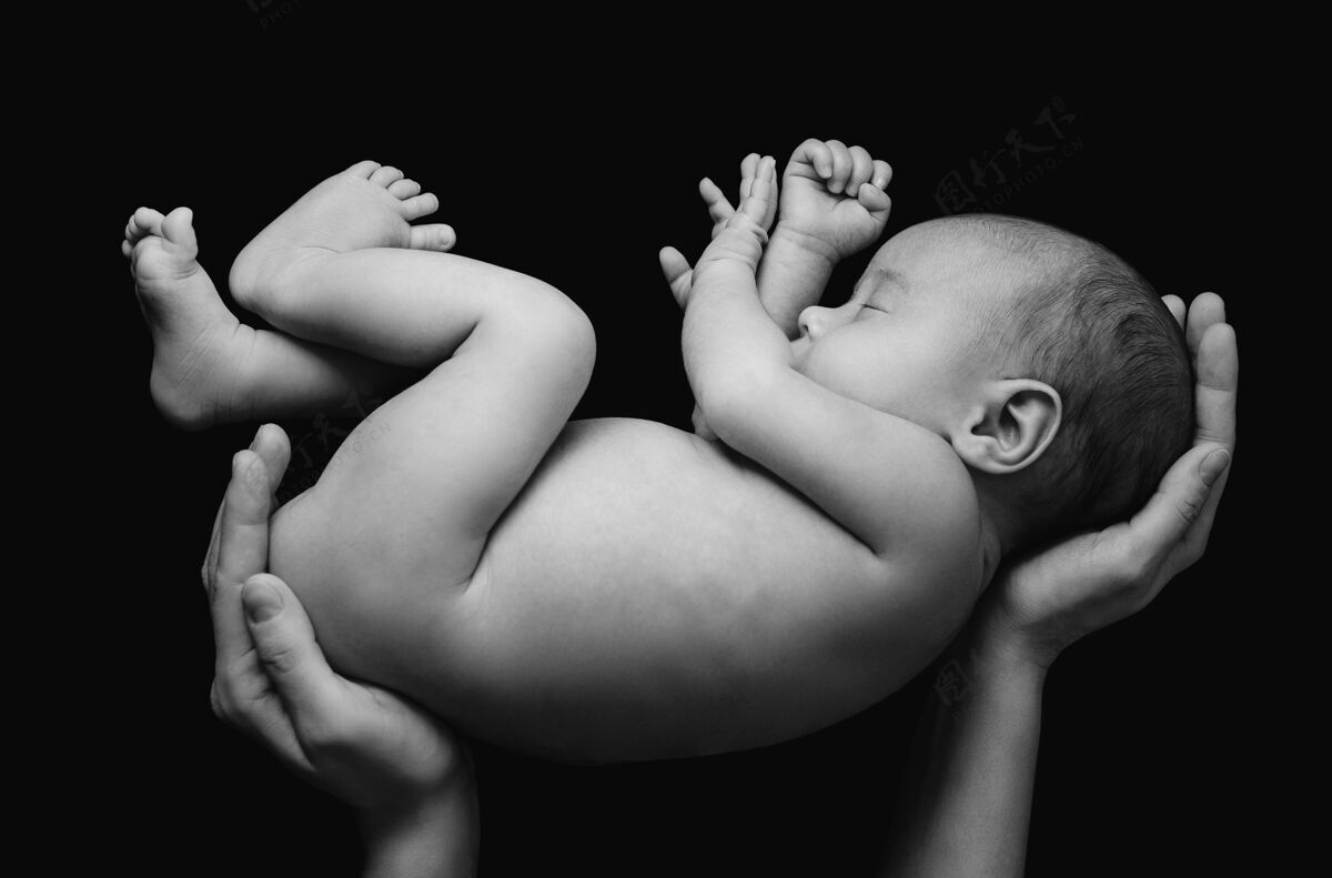 梦想可爱的新生婴儿在妈妈的手上贴着黑墙单色童年家庭