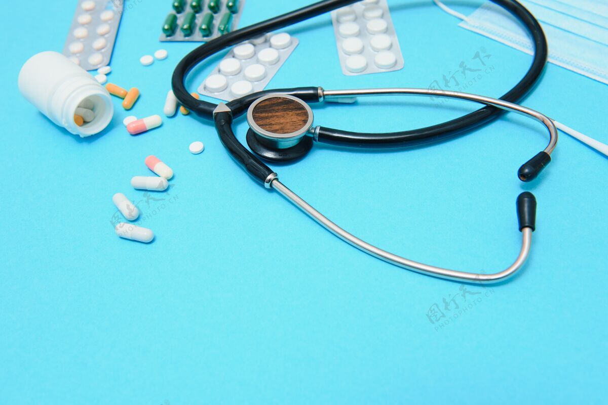 保健五颜六色的药片和胶囊装在盒子里 温度计 眼底镜 消毒瓶 容器 药片装在一个包裹里 都在蓝色背景的图像周围医疗胶囊顶视图