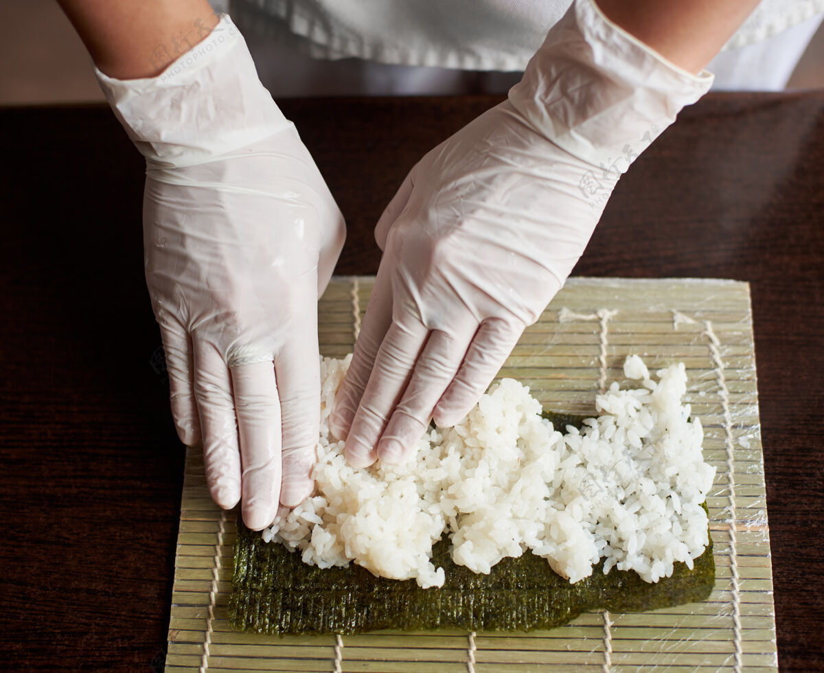 卷制作卷寿司过程的特写镜头竹席上的诺丽和白米厨师的手碰到米饭厨师开始做寿司持有海厨房