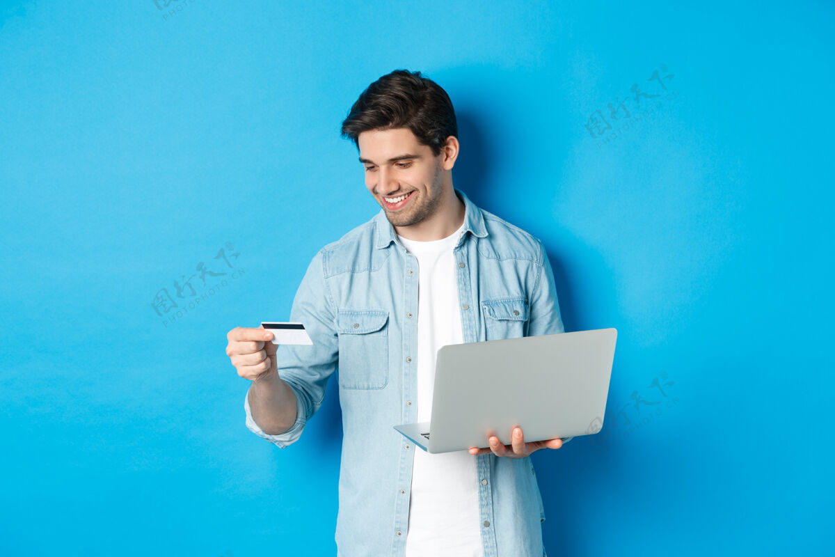 电脑年轻人在线订购 手里拿着信用卡和笔记本电脑生活方式成人贷款