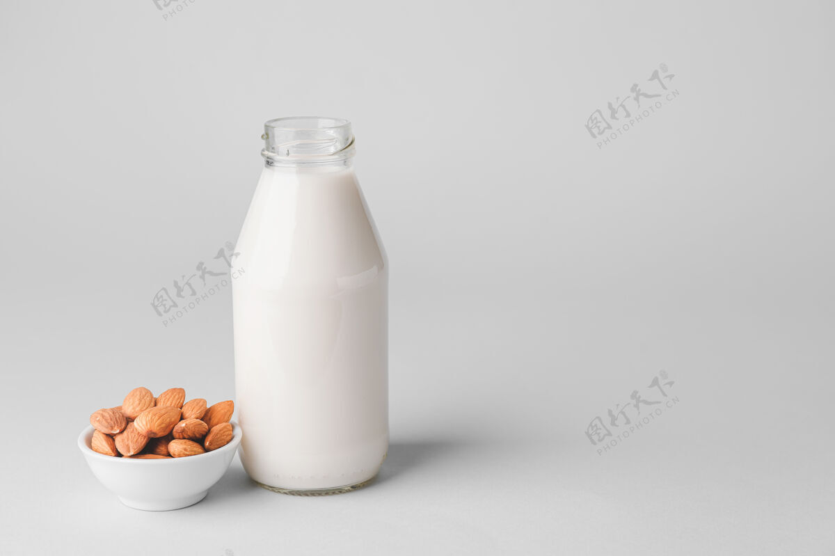 素食主义者一瓶美味的杏仁牛奶和一碗带坚果的浅色背景乳糖蛋白质过敏