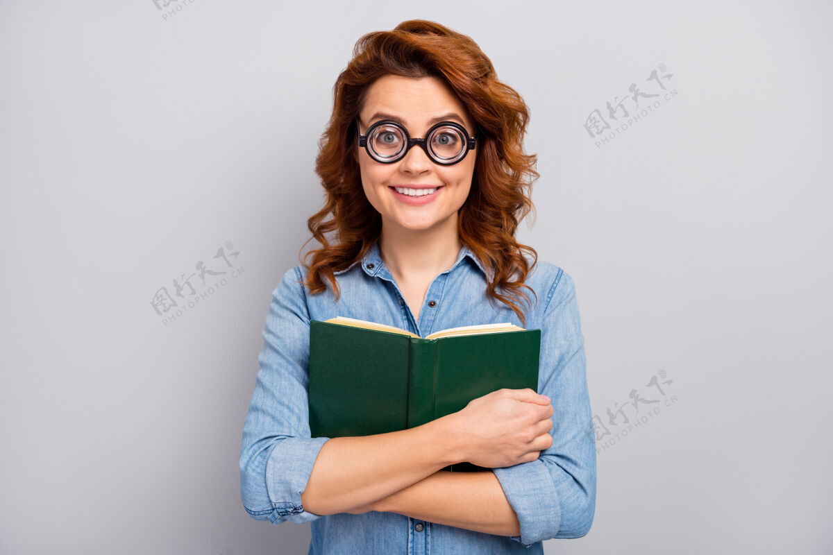欢乐滑稽 时髦 开朗 戴眼镜的女人的肖像拥抱最喜欢的书故事穿着时髦的衣服隔着灰色的墙情感牛仔时尚