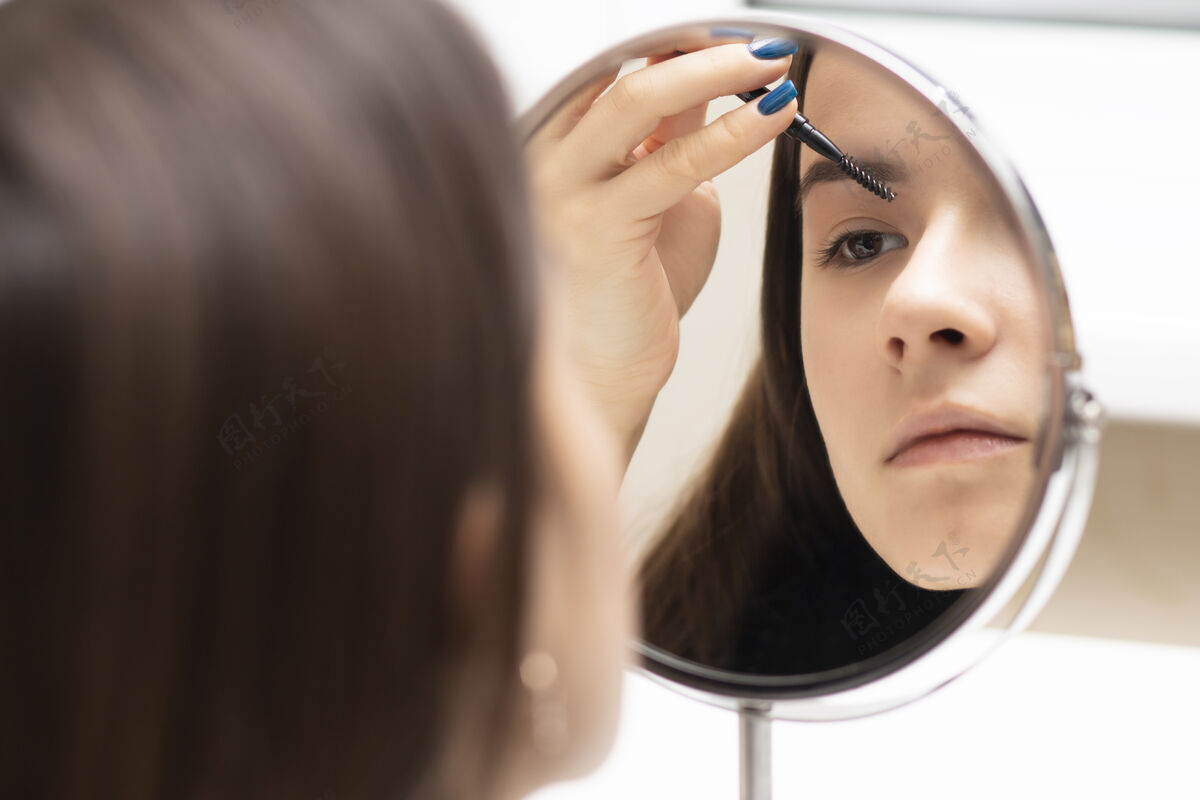 年轻一个年轻女子一边化妆一边照镜子铅笔魅力制造