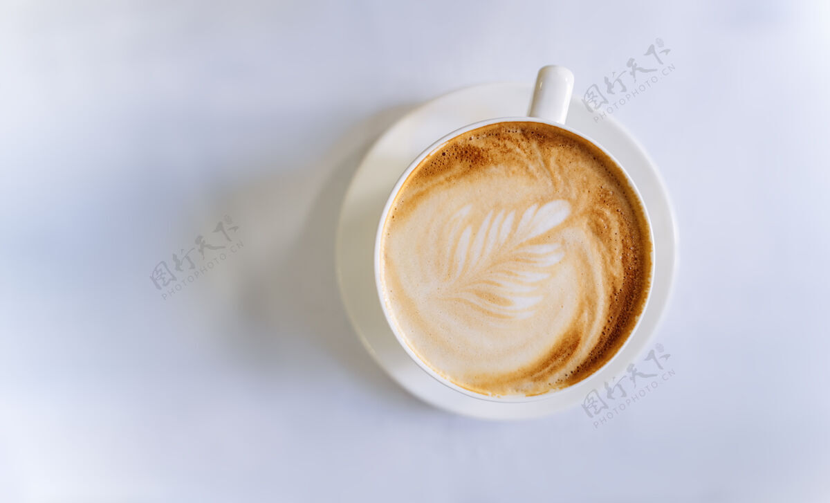 刷新一杯咖啡的顶视图白色桌子上有漂亮图案的咖啡杯子饮料木头