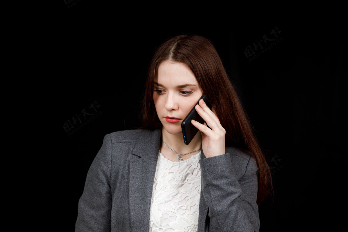 沟通快乐而成功的年轻时尚博主在电话里动情地交谈穿着休闲灰色夹克的漂亮年轻女子手里拿着智能手机设备积极微笑