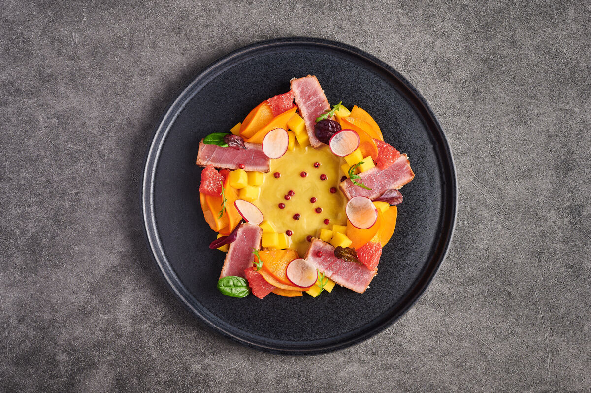 芒果金枪鱼牛排沙拉 芒果酱 香草和香料在一个黑暗的盘子 顶视图 复制空间 食品装饰的概念光烤健康