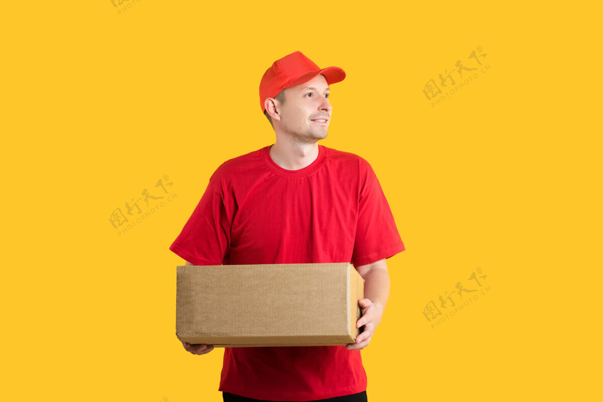 工人身穿红色制服的男子信使手里拿着一个黄色的空科尔顿盒子年轻快乐盒子