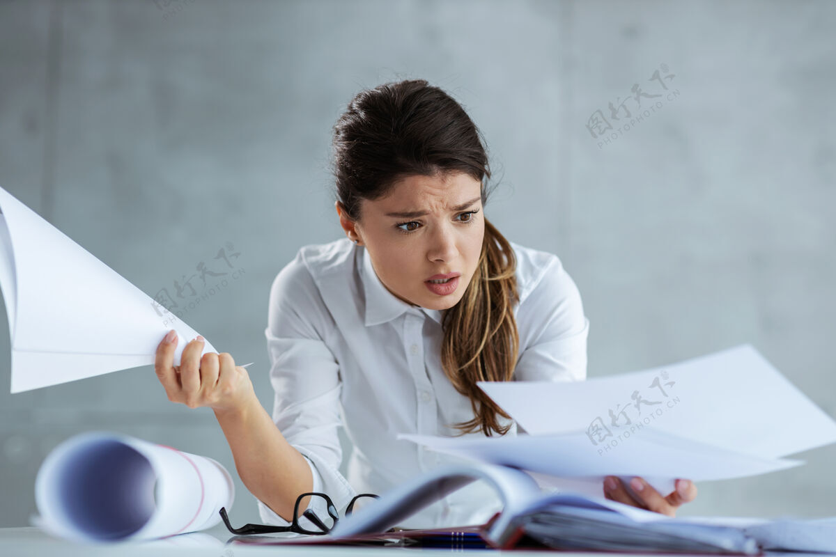 野心忙碌的女建筑师靠在桌子上看文件桌子上有蓝图思考工作商人