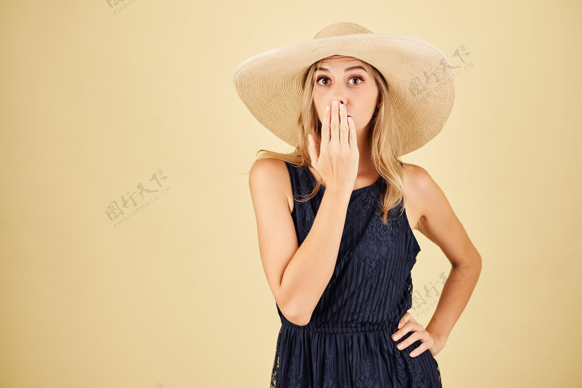 成人一个穿着考究的裙子 戴着草帽捂着嘴的惊讶的年轻女人自信微笑快乐