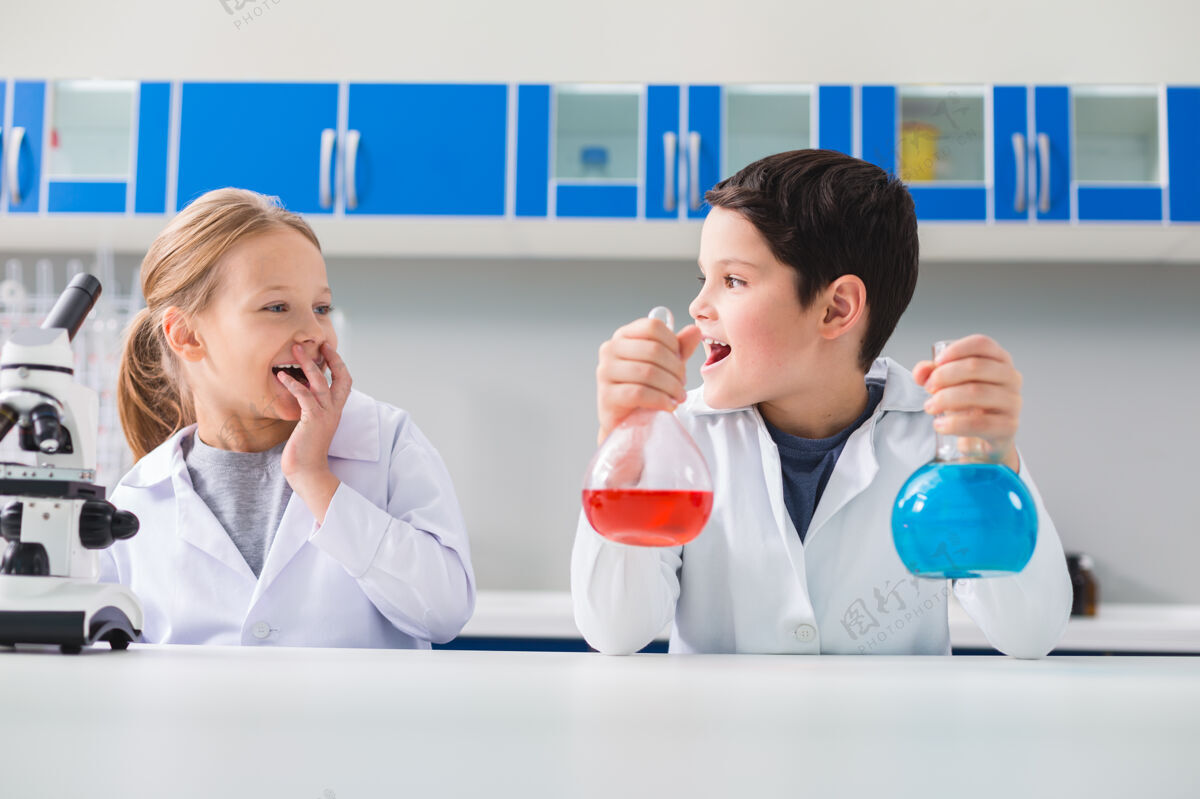 生物技术在实验室里玩得很开心快乐的好男孩拿着装有试剂的瓶子 看着他的朋友 同时在实验室里玩得很开心发现课堂实验室