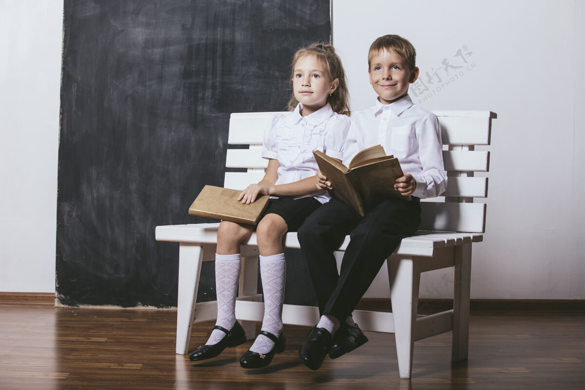 教育快乐的男孩和女孩从小学班的板凳上看书的背景板学童堆栈坐着
