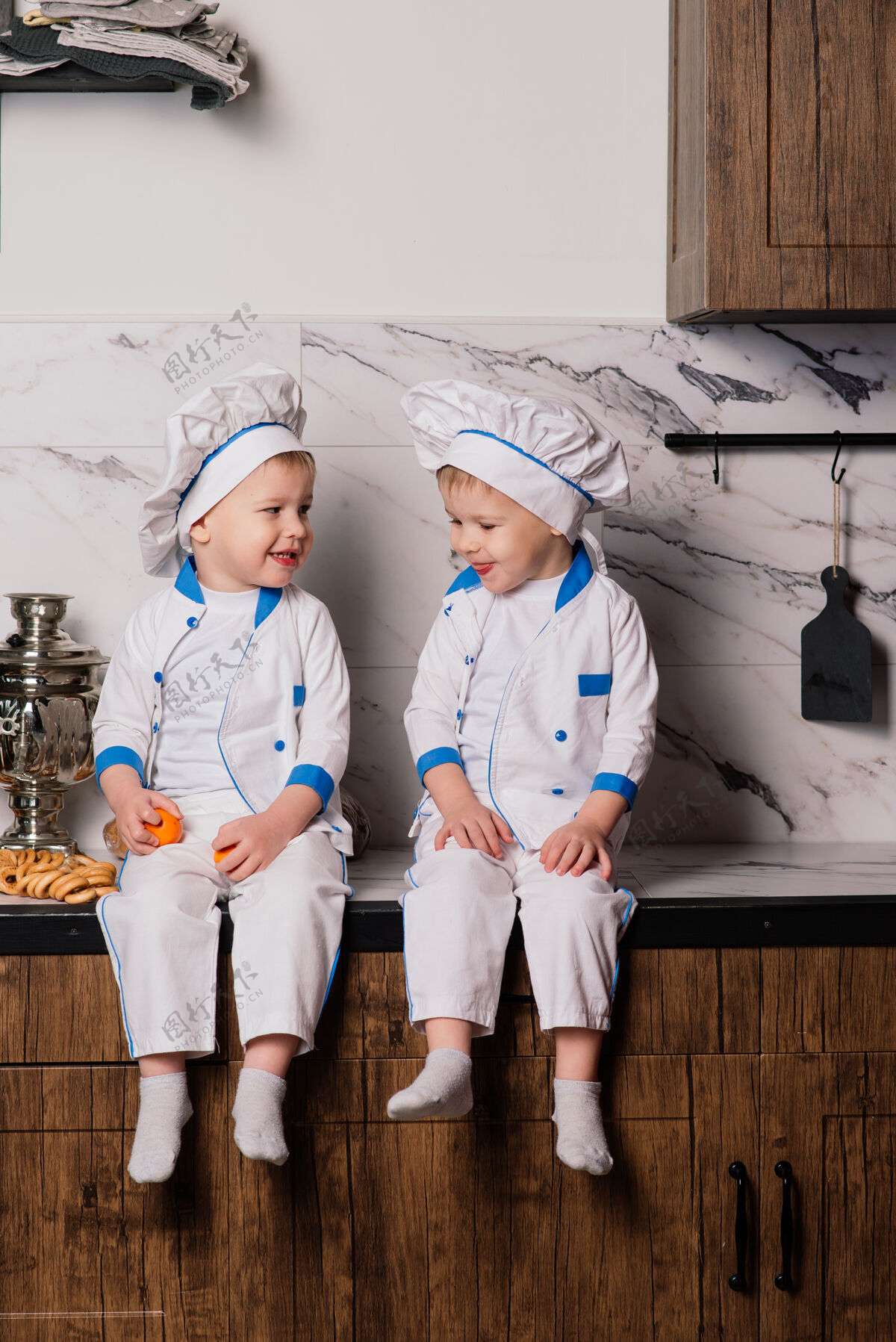 童年小可爱的厨师拿着餐具坐在厨房里 双胞胎兄弟 橘子 百吉饼厨师欢乐厨房
