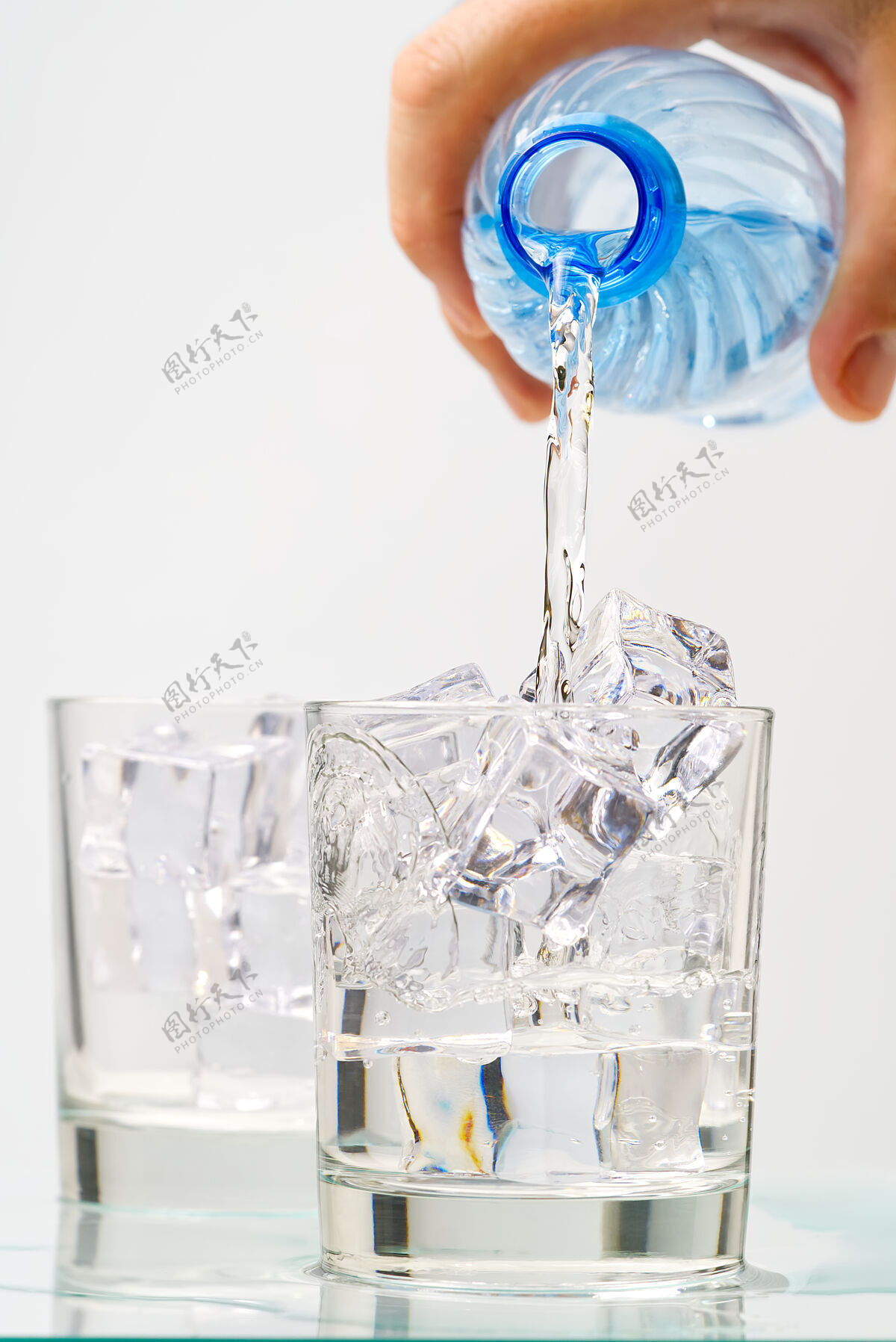 飞溅把干净的饮用水从蓝色塑料瓶倒进蓝色背景的玻璃里环保纯净瓶子