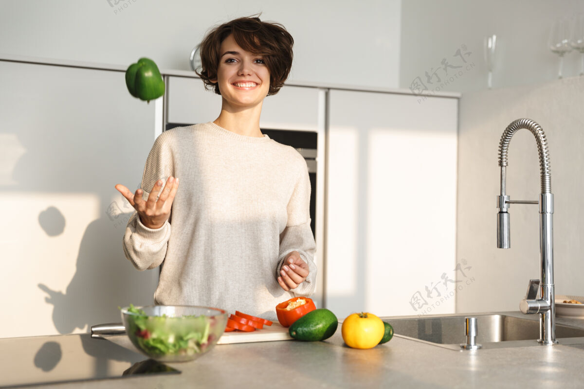 肖像快乐的年轻女子在家的厨房做新鲜沙拉素食新鲜蔬菜