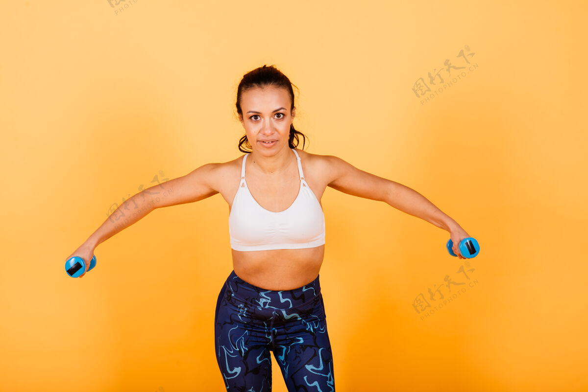 健身强度和动机完全穿着运动服的年轻苗条的非洲妇女在黄色背景下的工作室里锻炼身体的长度人运动员减肥