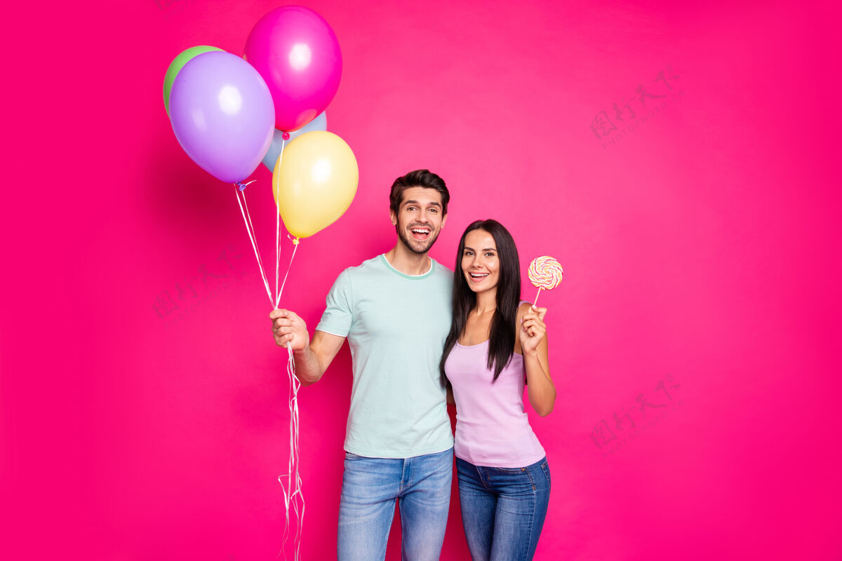 家庭照片中搞笑的男女手拿着气球来到父母的生日派对上与糖邦邦穿休闲装孤立的粉红色背景氦头发女孩