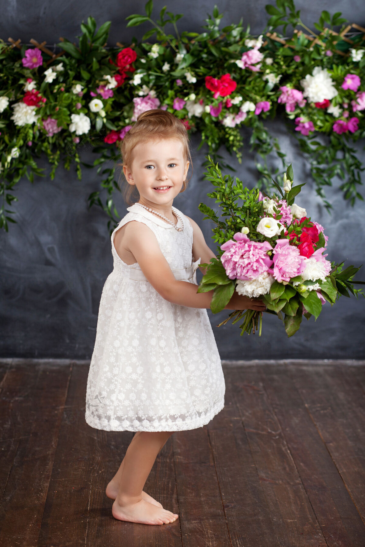 自然可爱的小女孩带着一束鲜花的肖像花看对着镜头夏天童年房子