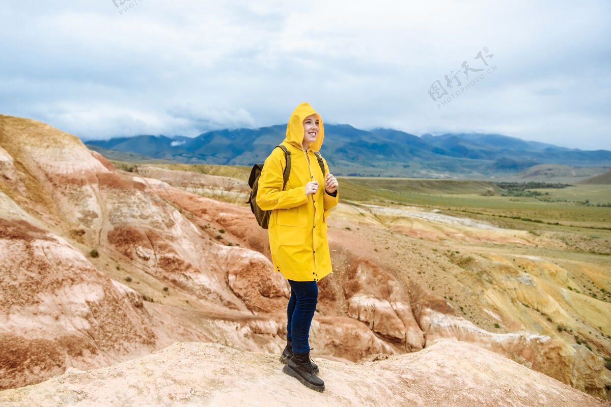 山快乐的女徒步旅行者背着背包 在多云的天气里走在山里女人山谷旅行者