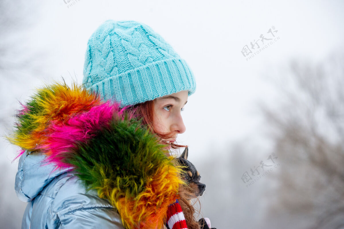 少年冬日少女的画像在她的温暖服装.青少年穿蓝色衣服的女孩帽子女孩和吉娃娃在一起时尚雪人