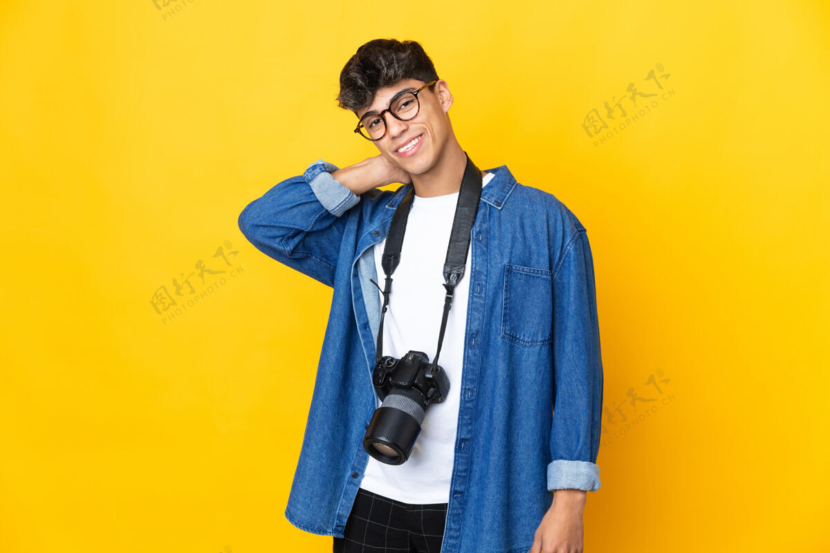 单反年轻的摄影师越过隔离的黄色墙壁大笑年轻男人人