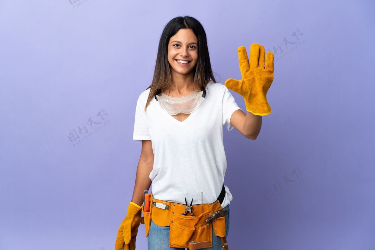 成功年轻的电工女人被隔离在紫色的墙上用手指数着五个工匠成人车间