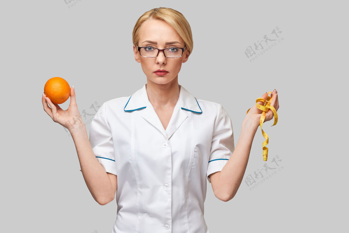 橘子水果营养师医生健康的生活方式概念-持有有机新鲜橘子水果和卷尺柑橘免疫力概念