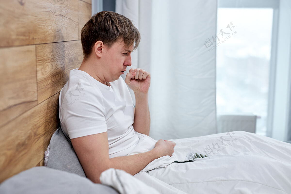 爆发患有covid-19症状的男子躺在家中的床上 高烧和咳嗽使他无法过正常的生活 他不得不自食其力-隔离停留回家病人床流行病