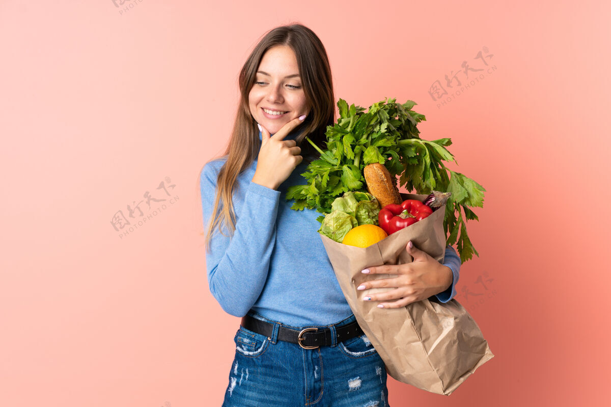 购买年轻的立陶宛妇女拿着一个杂货购物袋 面带微笑地看着旁边产品成人年轻