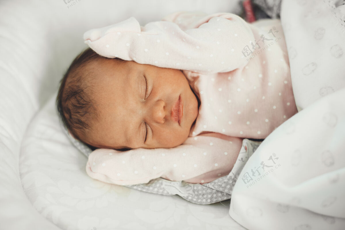 甜蜜上图是一个穿着可爱衣服睡在床上的新生婴儿衣服年轻睡眠