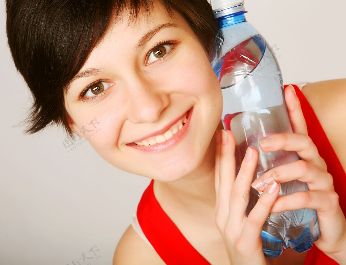 健康漂亮的女人拿着一瓶干净的水提神现代微笑