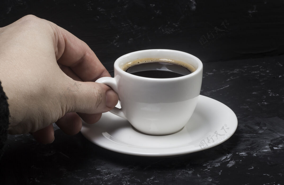卡布奇诺一个女人拿着一个白色的杯子 手里拿着一杯黑咖啡来品尝它的味道液体上瘾抽象